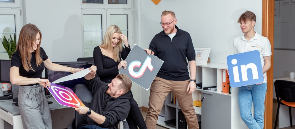 Grupa osób w biurze trzymających znaki w mediach społecznościowych w ramach swojej strategii marketingowej.
