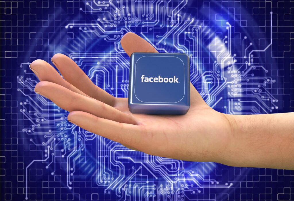 Dłoń osoby trzymającej mały kwadrat ze słowem „Facebook”, przedstawiająca jej strategię marketingu cyfrowego.